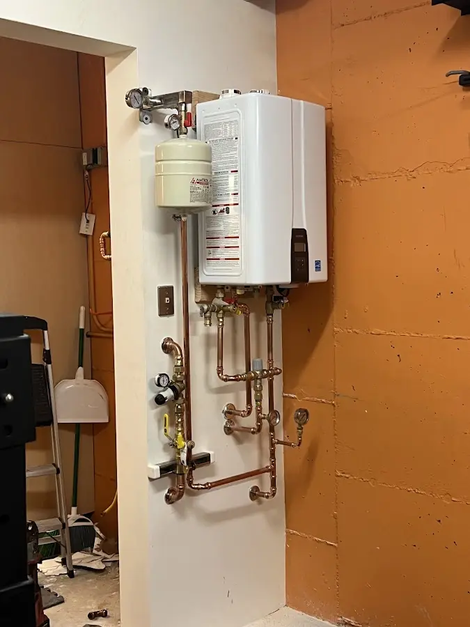Plumbing technician inspecting water heater connections in Sunapee